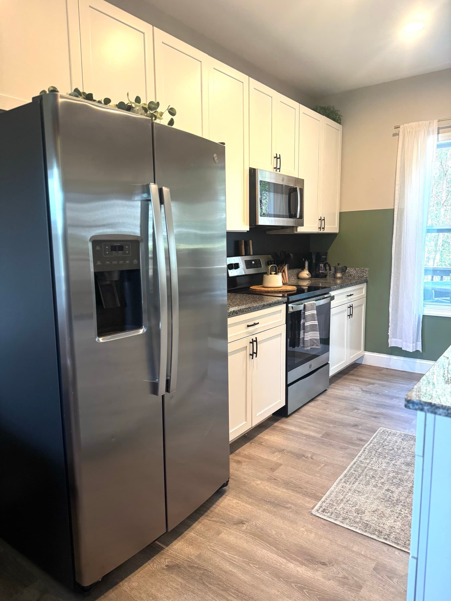 Full kitchen with stainless appliances, white cabinets, and dark counters