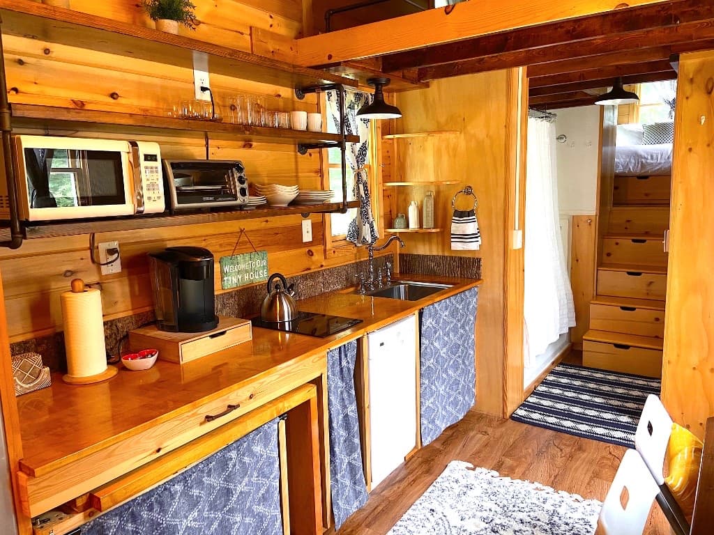 Kitchenette with open shelving, cooktop, and loft stairs with storage drawers