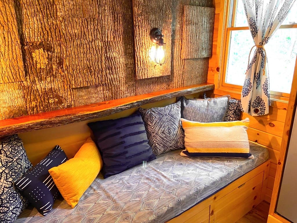 Close-up of the bark accent wall daybed with pillows and Edison sconce